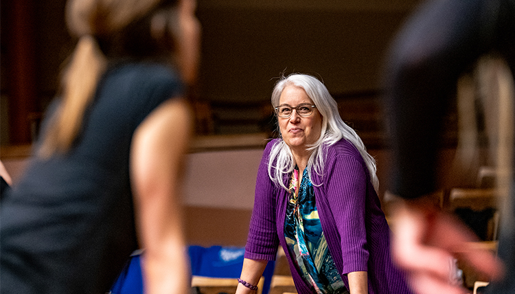 dance director Suzanne Ostersmith leans on stage with student dancers