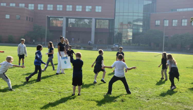 Young students play educational games on lawn
