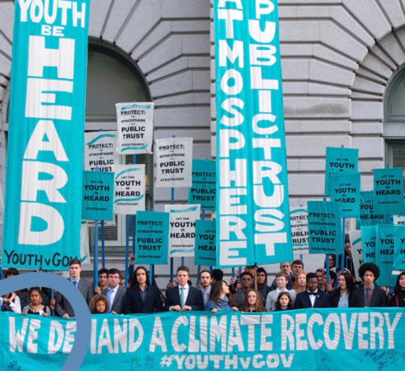 Young people hold large signs that read we demand a climate recovery.