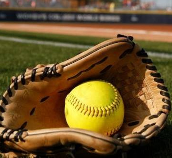 A bright yellow softball sits in a mitt