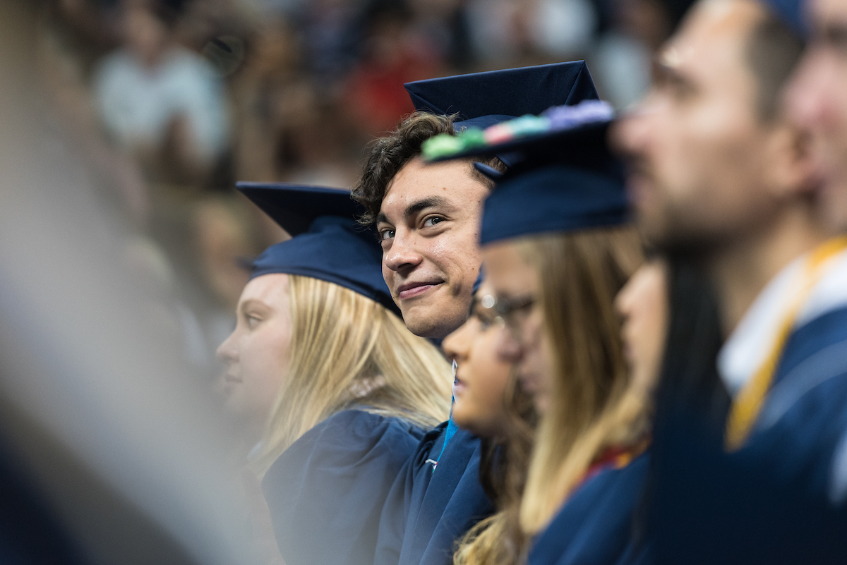 Students sitting and wearing commencement attire