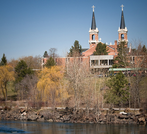 A view of the spires of St. Aloysius with the Spokane River in the foreground