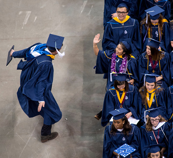 An undergraduate student high-fives his friend after receiving his diploma