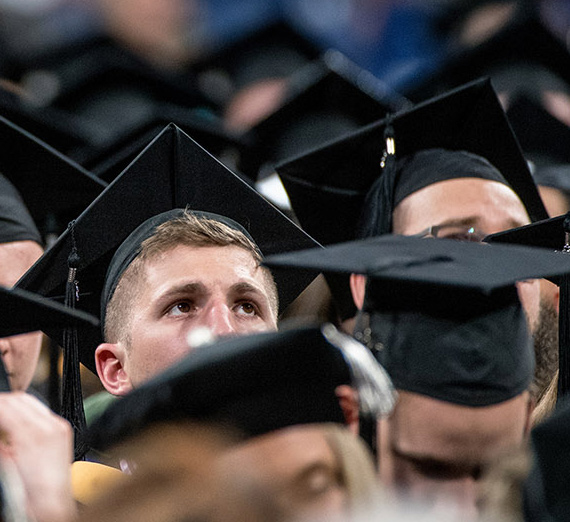 A graduate student peers above the crowd of mortar boards