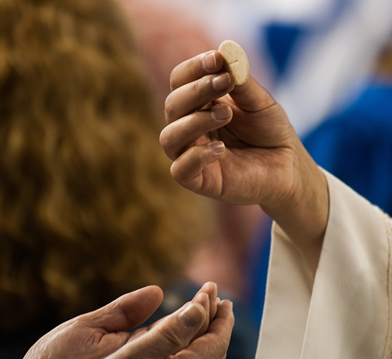 A graduate receives a communion wafer at Commencement Mass