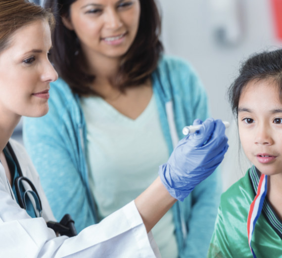 A doctor tests the vision of a child with a light