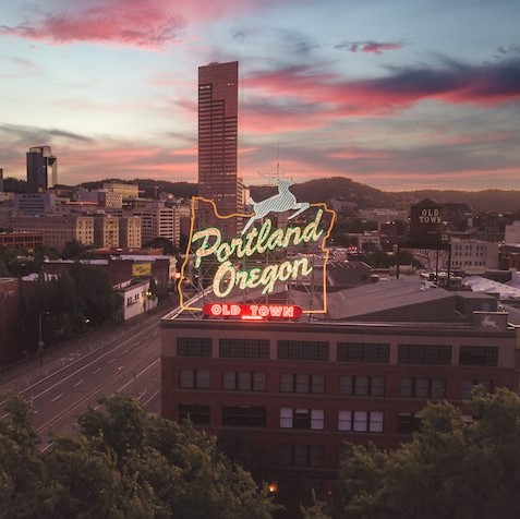 View of the illuminated Portland Oregon sign against a pink and blue sunset