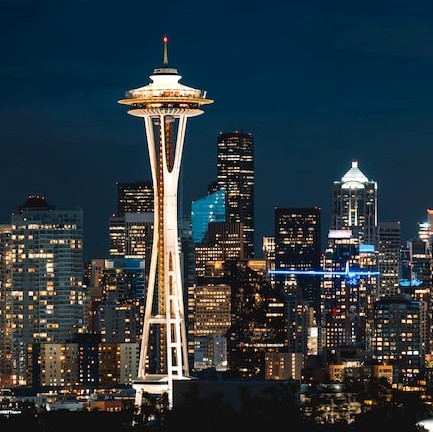 The Space Needle shines brightly against the cityscape of Seattle on a dark night