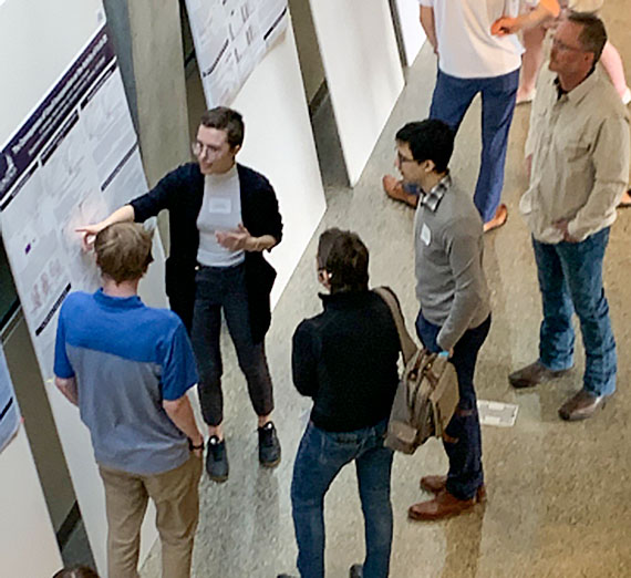 Two women stand in front of a presentation board. They are talking with each other.