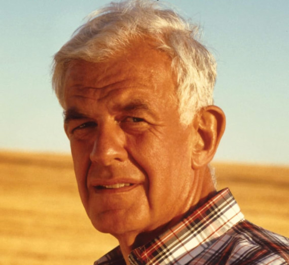 Headshot of Tom Foley standing in front of a wheat field.