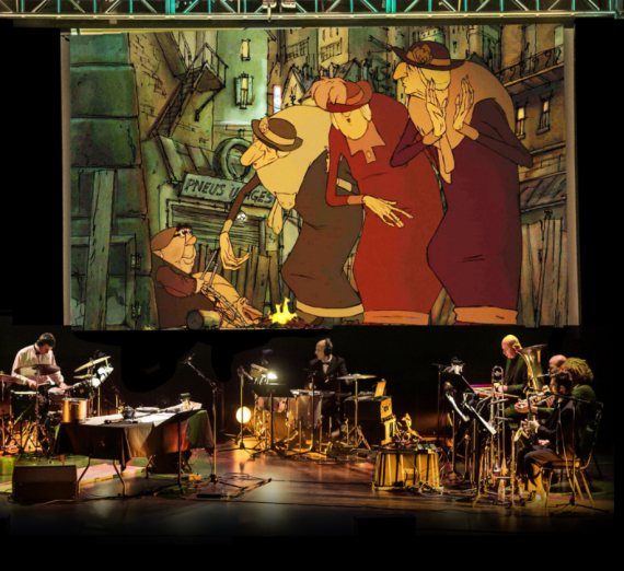 Musicians on stage playing while the Trilpets of Bellville movie plays on a large screen. 