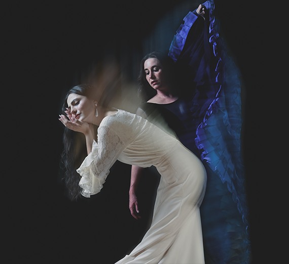 Two Flamenco dancers, one in a white dress, one in a blue dress. 