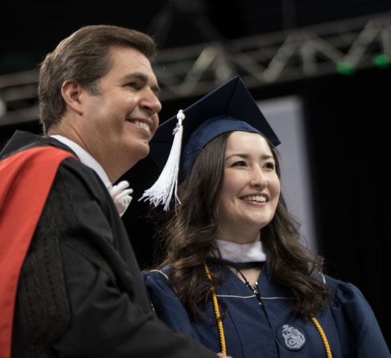 President Thayne McCulloh posing for a a photo with a student at Commencement 