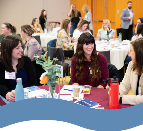 3 women at a table laughing and conversing.
