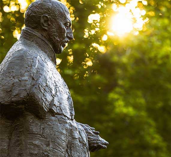 st ignatius statue with sun and trees behind it