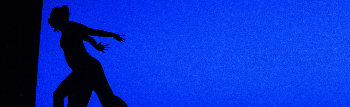 Silhouette of a dancer in front of a blue background.