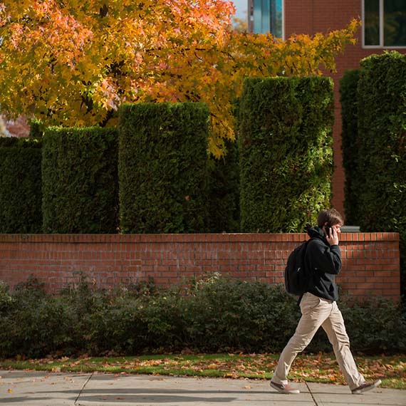 Student walking on campus while on the phone.