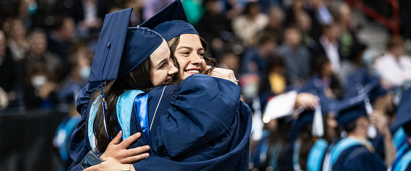 Two students hugging during the graduation commencement.