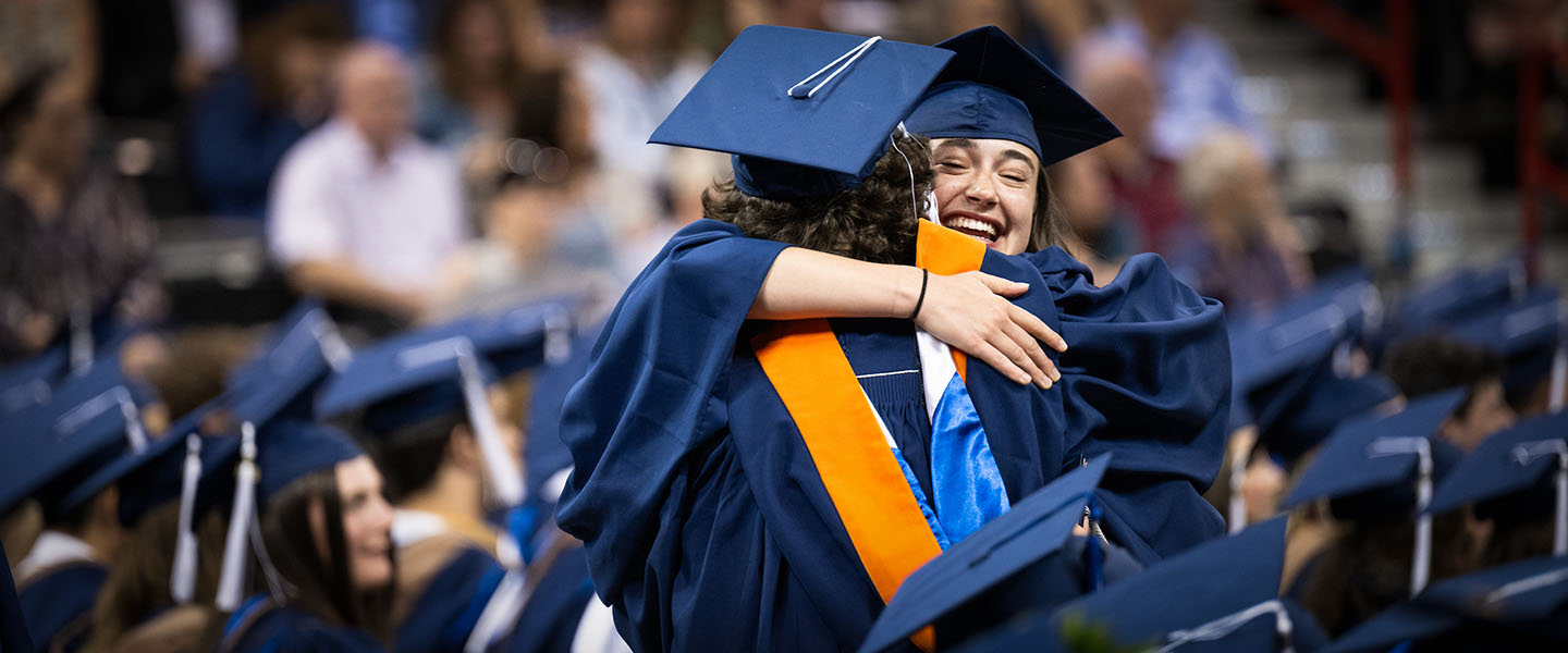 Graduating students hugging in a crowd.