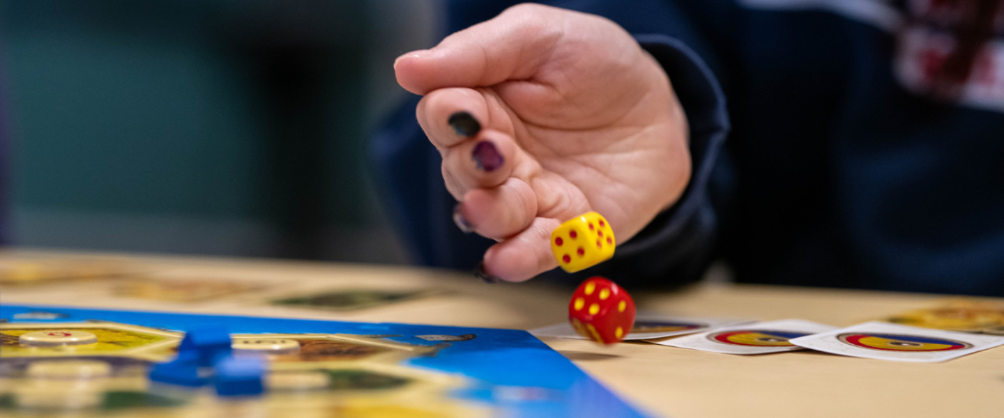 A hand releasing two dice for a roll on a game board. 
