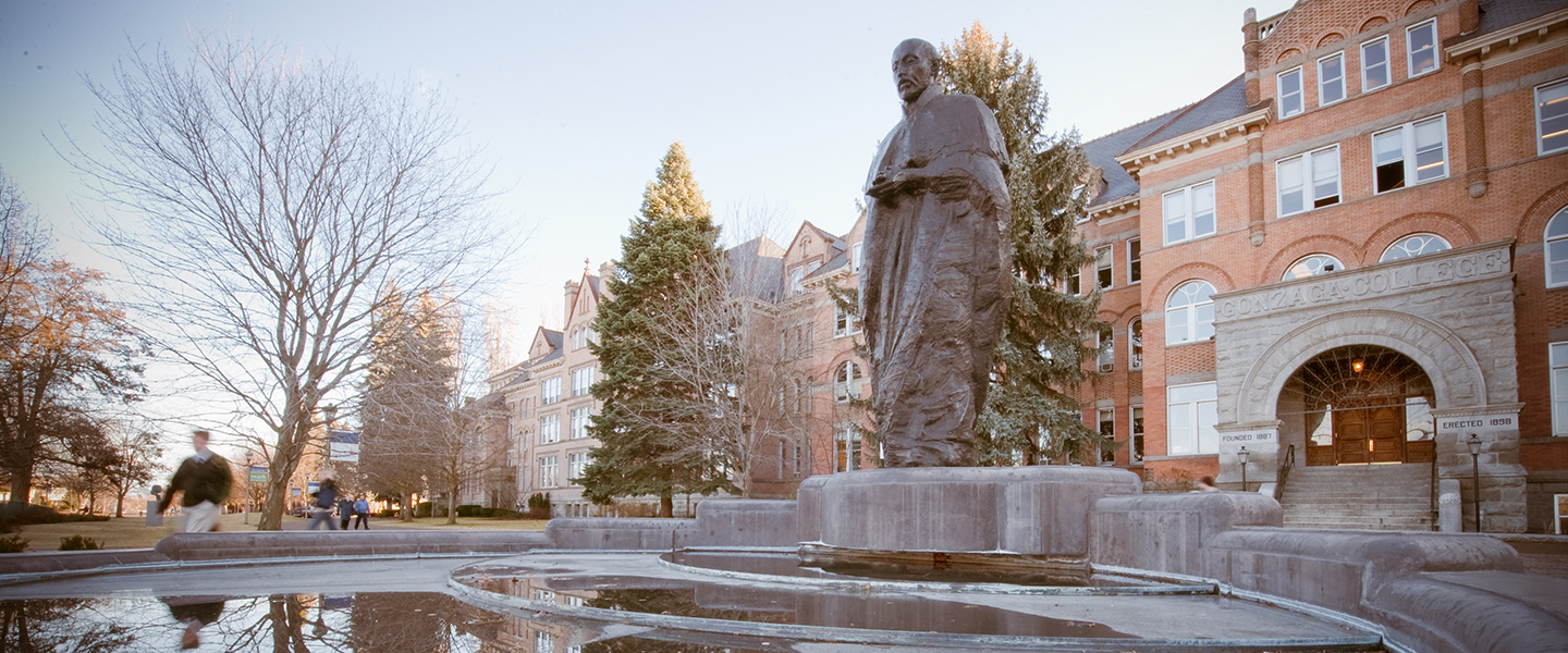 Statue of Saint Ignatius Loyola in foreground with Gonzaga University College Hall in the background.