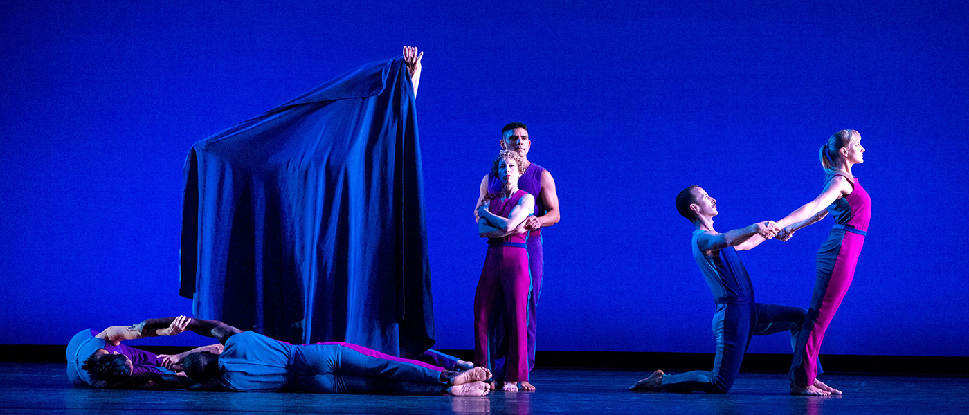 Dancers pose on stage with blue background.