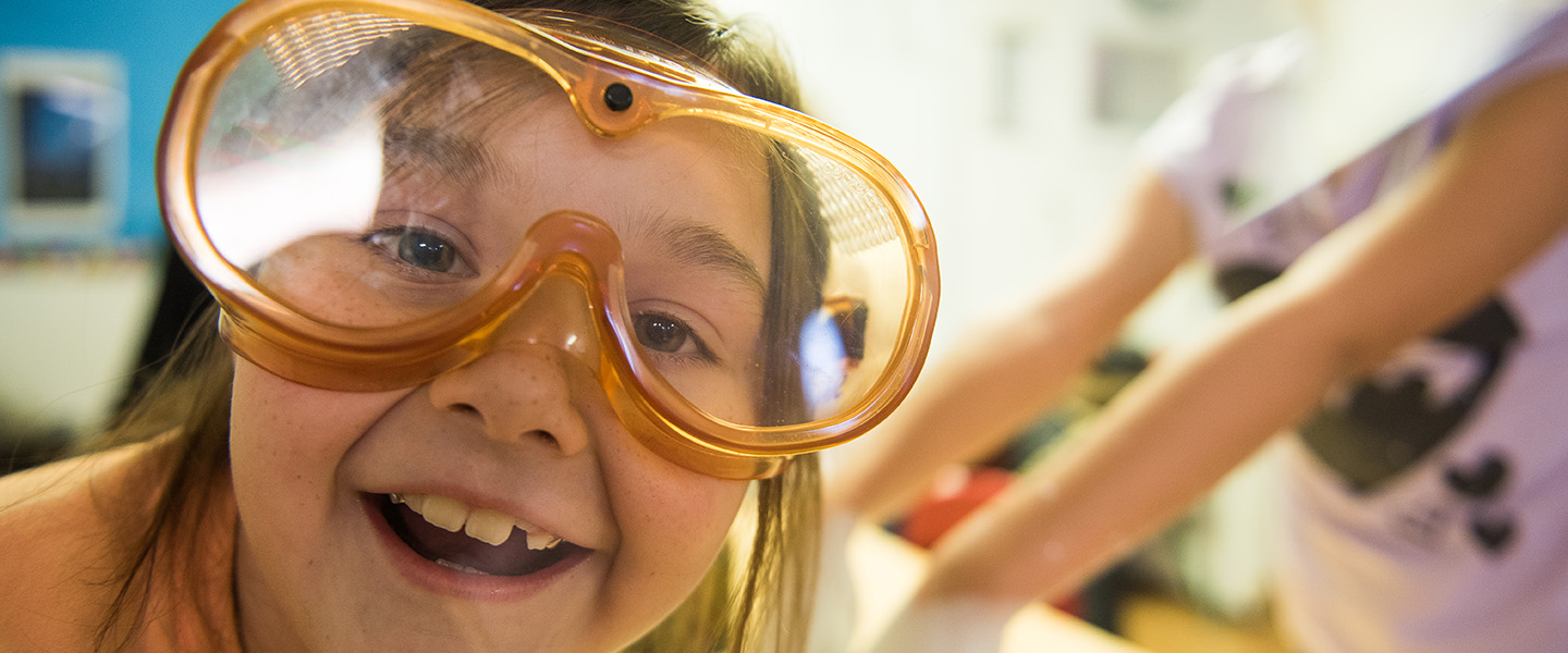 Close-up face of elementary student with science safety glasses.