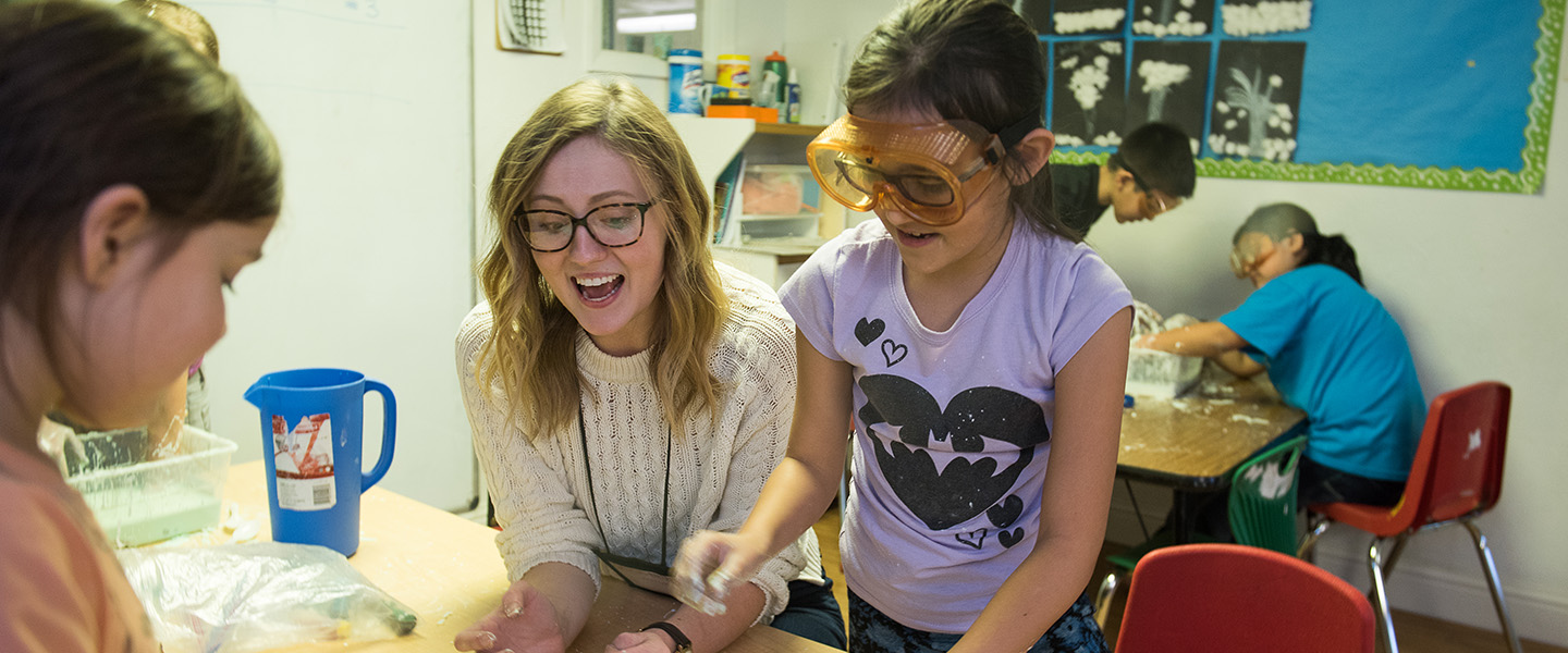 ������ student instructor leads elementary students in science experiment.