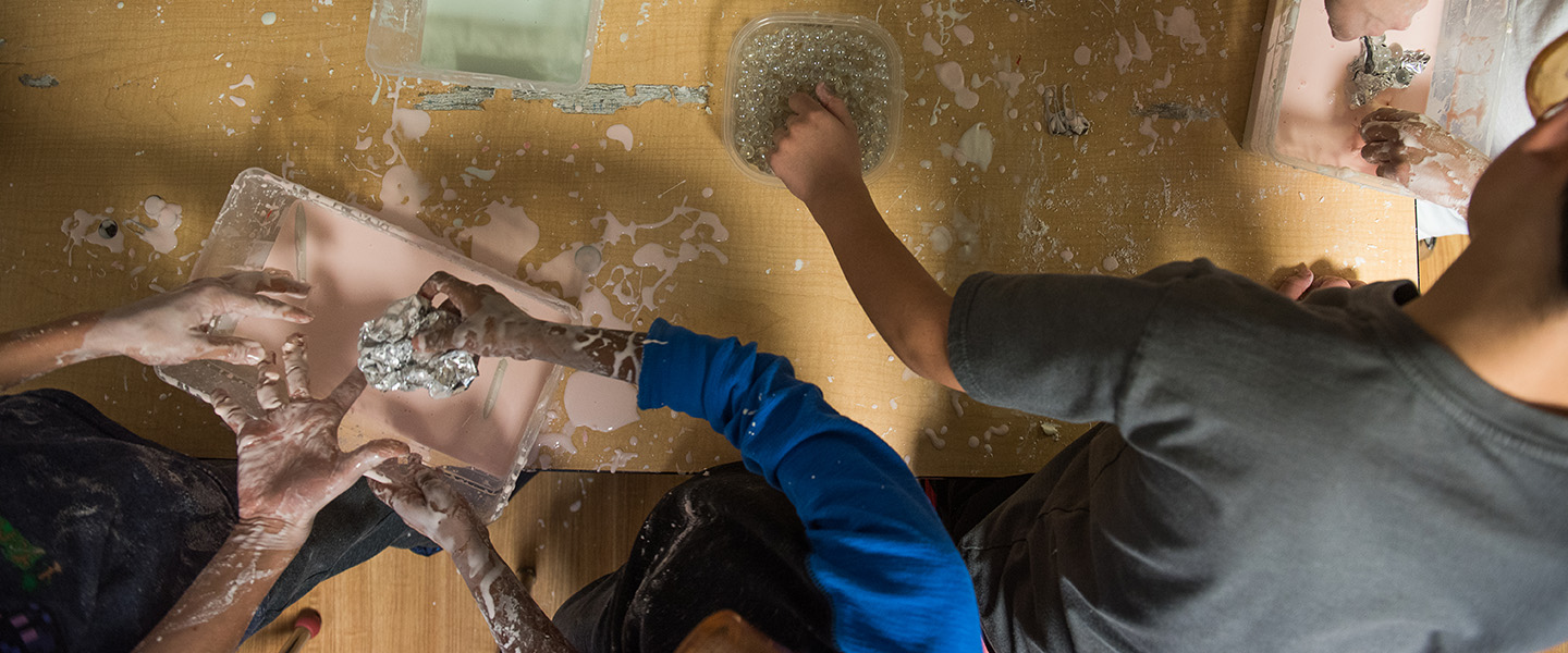 Decorative image looking down on hands in slime buckets.