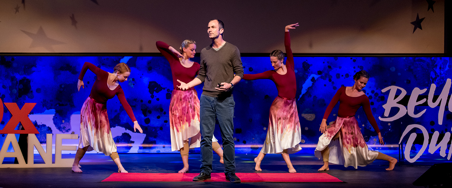 speaker with dancers on stage at TEDx event