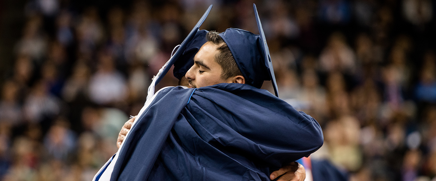 grads hug at commencement