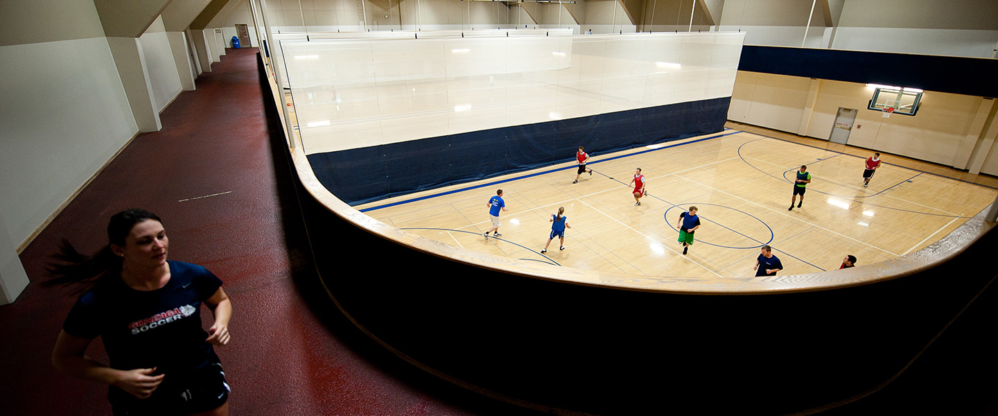 Student running around basketball courts at Rudolf Fitness Center.