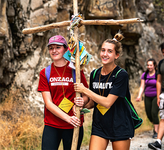 two students carrying a handmade cross