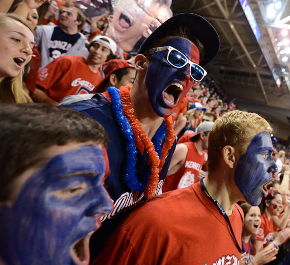 Gonzaga University students with their faces painted cheering in the Kennel Club student section at a basketball game 