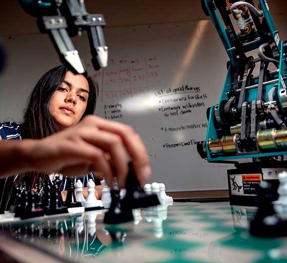 Student plays a chess game with a robot opponent.