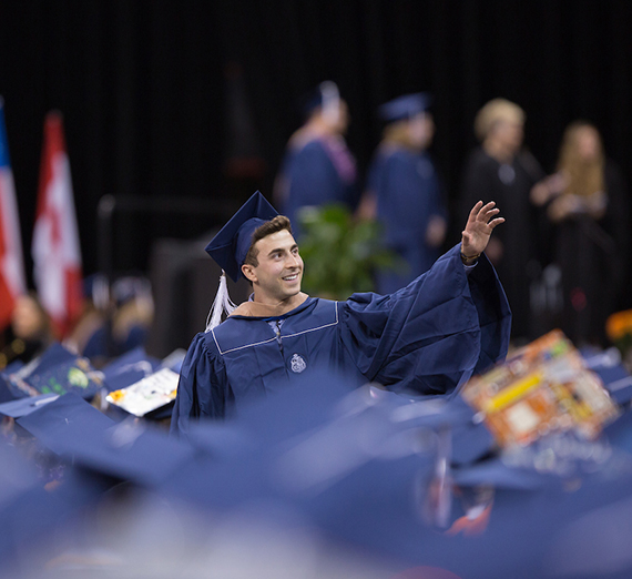 Student at the 2017 Undergraduate Commencement waving to the crowd