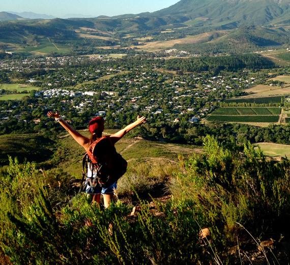 A study abroad student hiking above a green valley.
