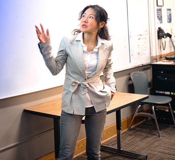 Female college teacher pointing at projector screen in classroom