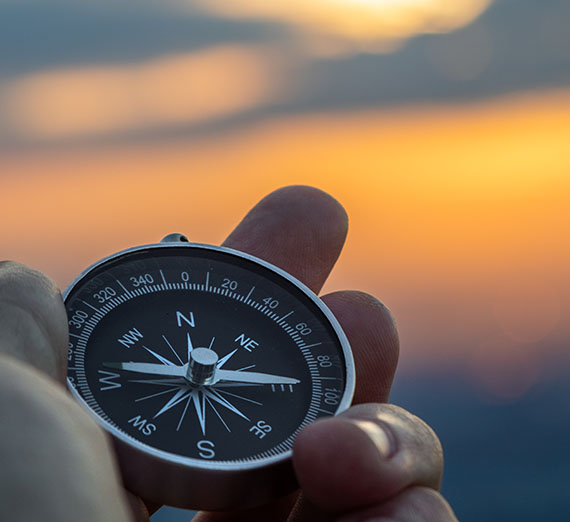 Compass in Hand with a blurred golden landscape in distance