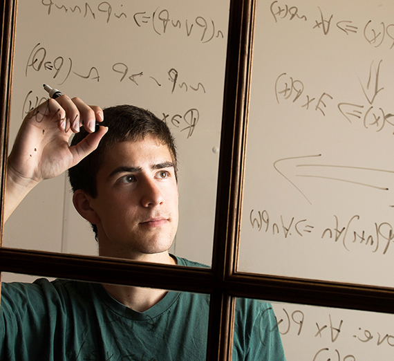 A Mathematics student works out a complicated problem on the board.