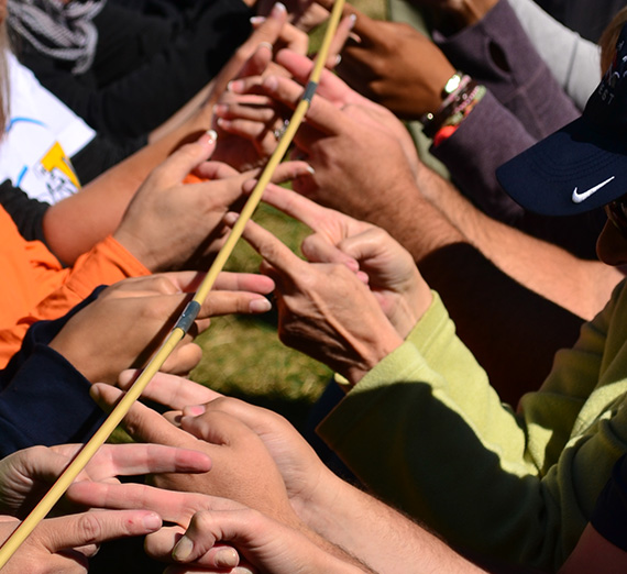 A group of people working together to hold a tent pole