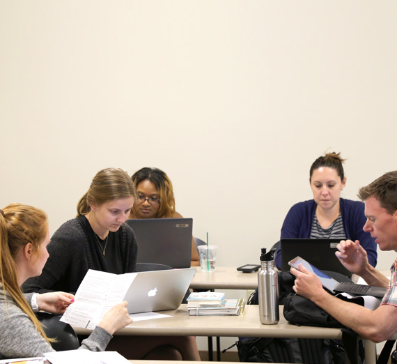 Students on computers discussing strategy