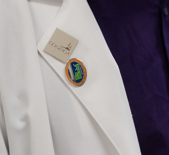 Pins signifying the Regional Health Partnership on a white lab coat.
