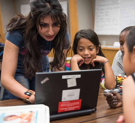 A teacher helping young students