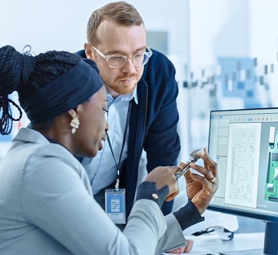 Male Supervisor Talks to a female Electrical Engineer who Works on Computer with CAD Software. Designing PCB, Microchips, Semiconductors and Telecommunications Equipment