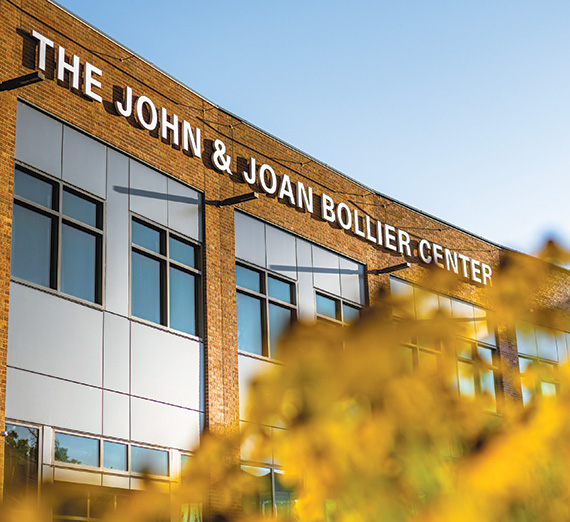 The Bollier Center building, viewed from an angle with yellow autumn leaves softly blurred in the foreground.