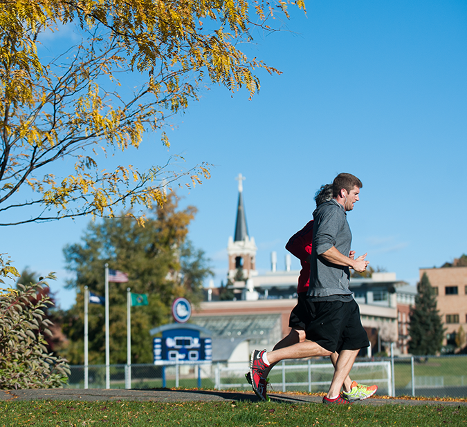 people running on campus with fall leaves