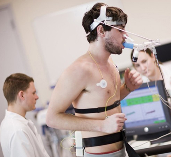 Runner on treadmill having electrocardiogram and metabolic testing performed by student researchers in Human Physiology Lab.