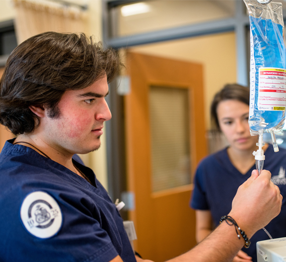 Two nurses examine an IV pack. 