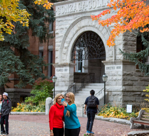 51�Թ� and parent take selfie in front of college hall 